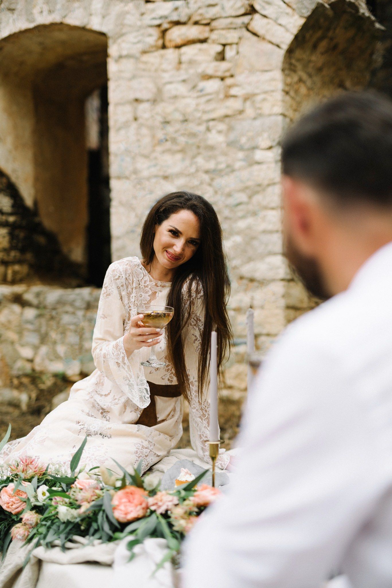 Elegant outdoor dining scene with stone wall backdrop and romantic table settings.