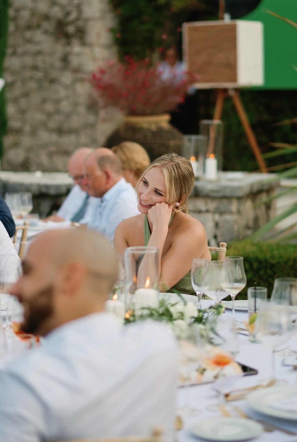 Guest at an outdoor wedding reception rests head on hand at an elegantly decorated dinner table.