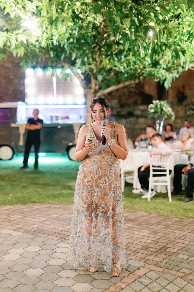 Guest gives emotional speech at outdoor wedding reception under tree canopy.