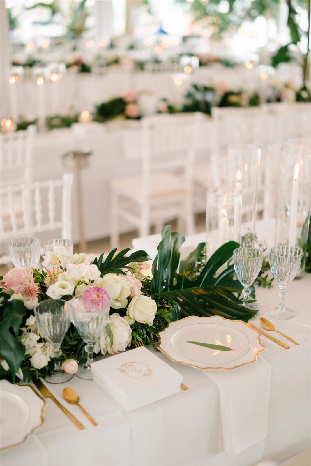 Elegant wedding reception table with white linens, gold cutlery, and floral centerpieces.