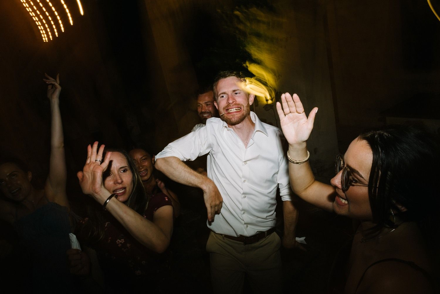 Party guests dancing enthusiastically under ambient lighting at a nightclub.