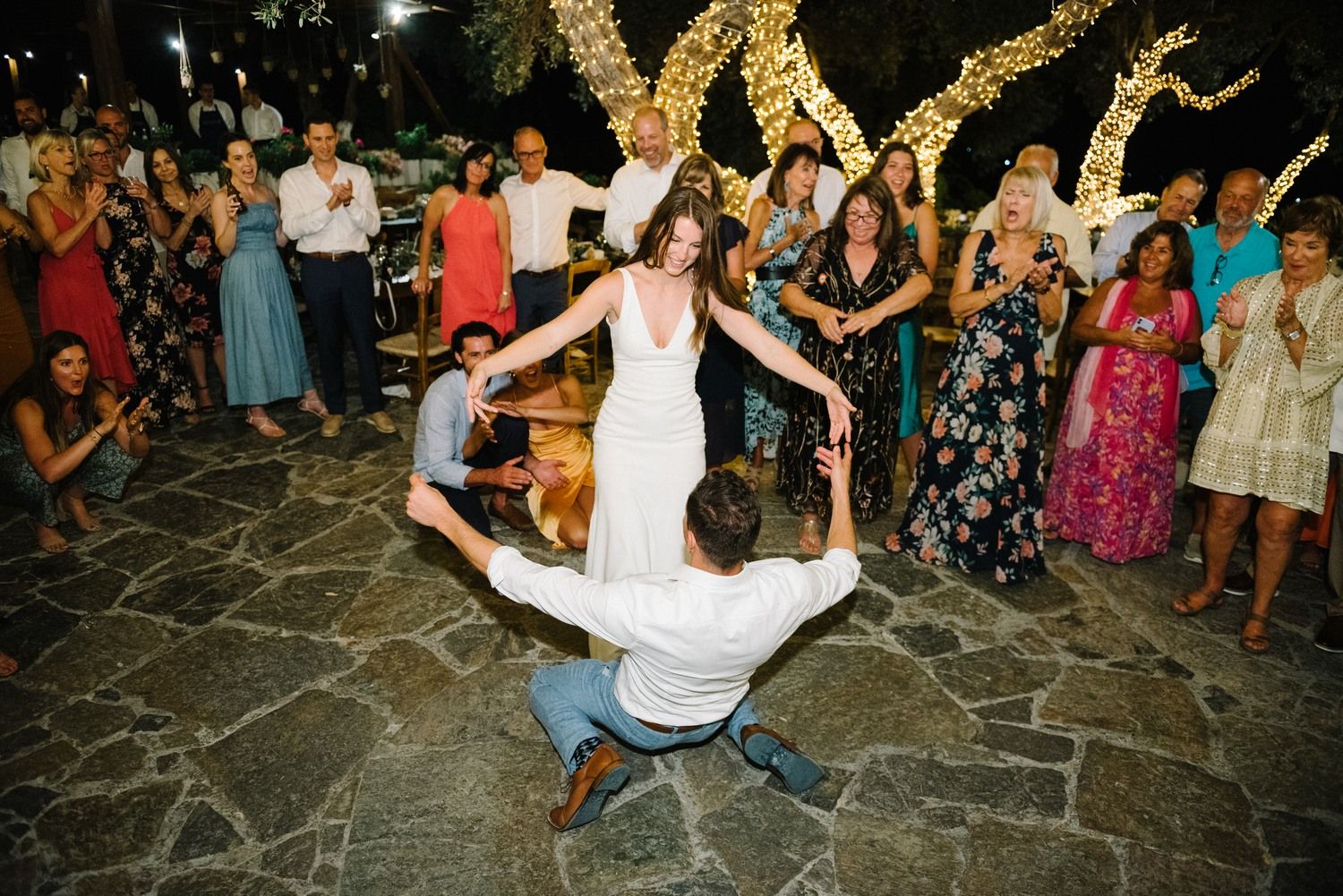Wedding reception dance featuring dramatic dip move on stone patio under evening lights.