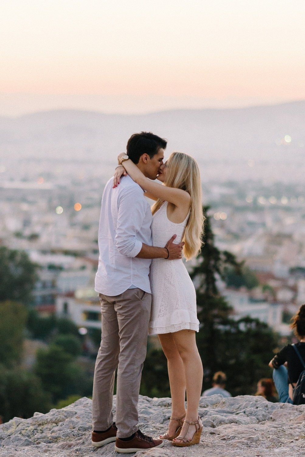 egagement kiss in  filopappou hill athens with an amazing sunset