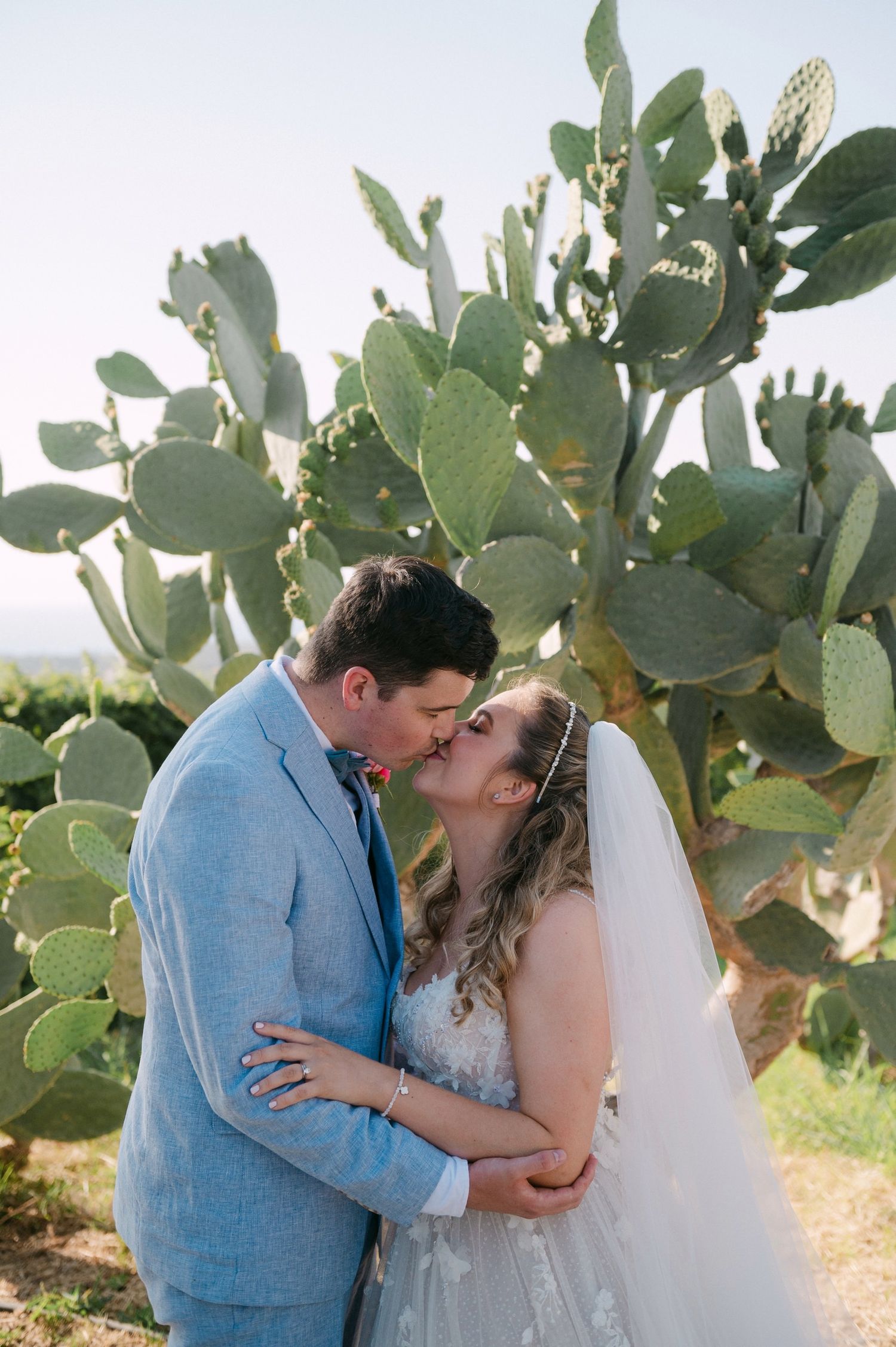Romantic wedding couple embrace in front of desert cactus garden at sunset.