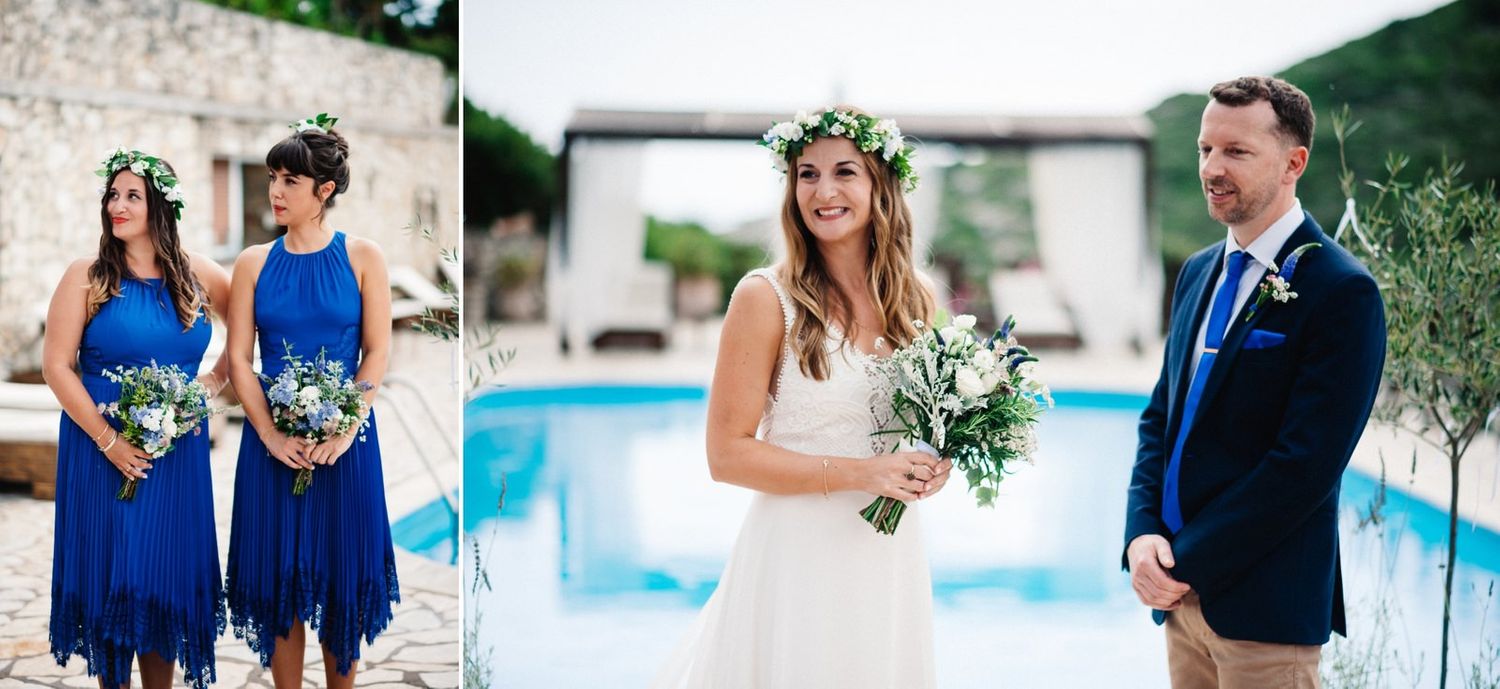 Wedding party in blue and white attire posing by pool at outdoor stone venue.