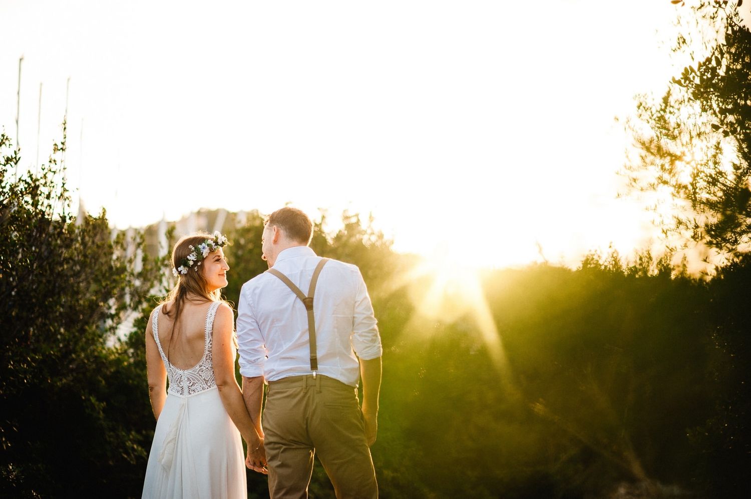 Newlyweds stand together against vibrant sunset lighting in a natural outdoor setting.