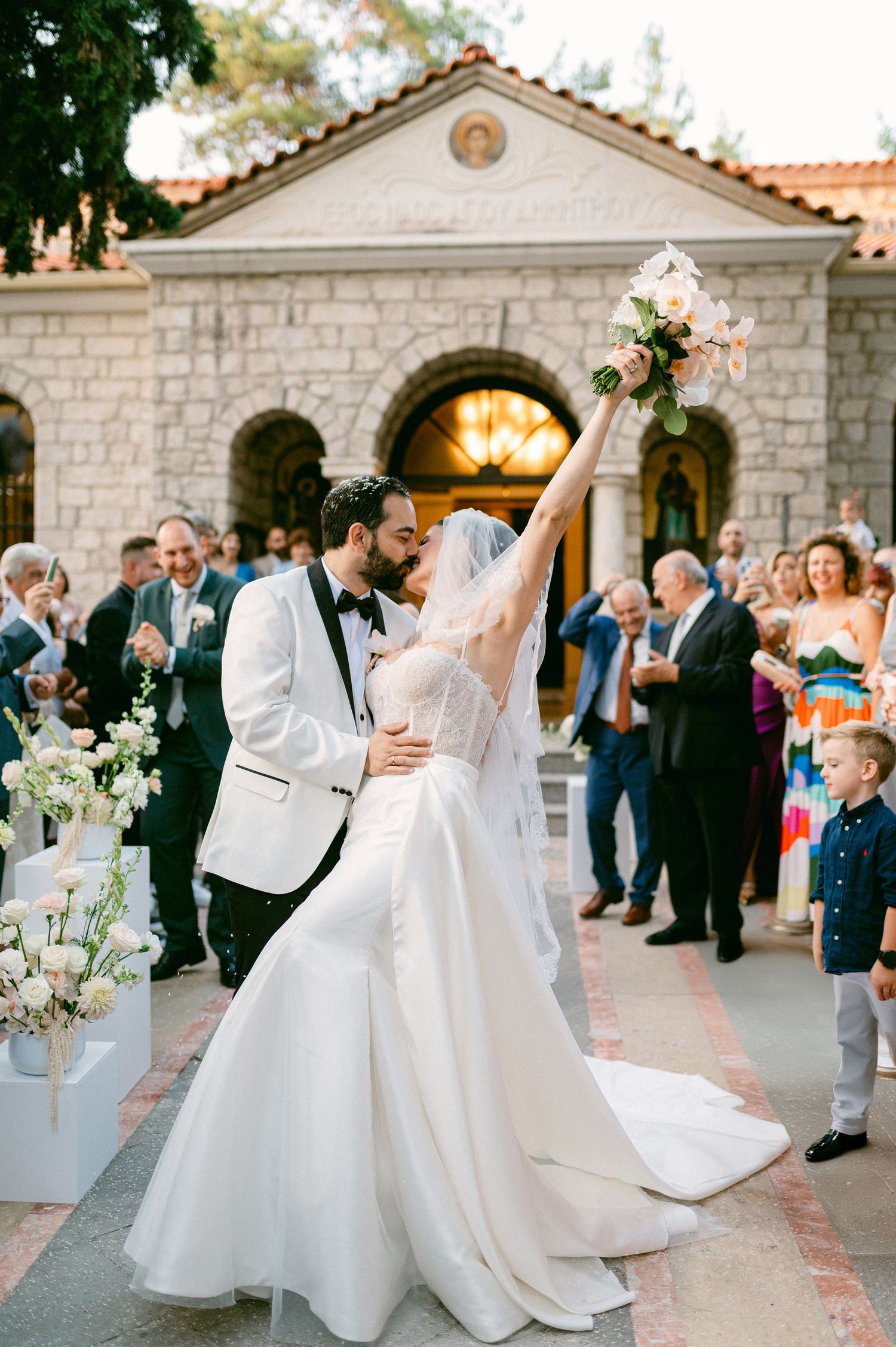 Elegant wedding reception celebration with guests dancing outdoors at a stone venue during sunset.