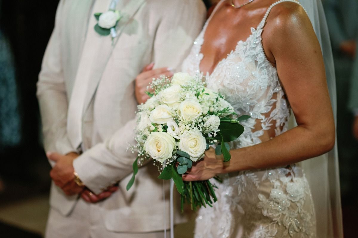 Close up of wedding couple's formal attire and white rose bouquet during ceremony.
