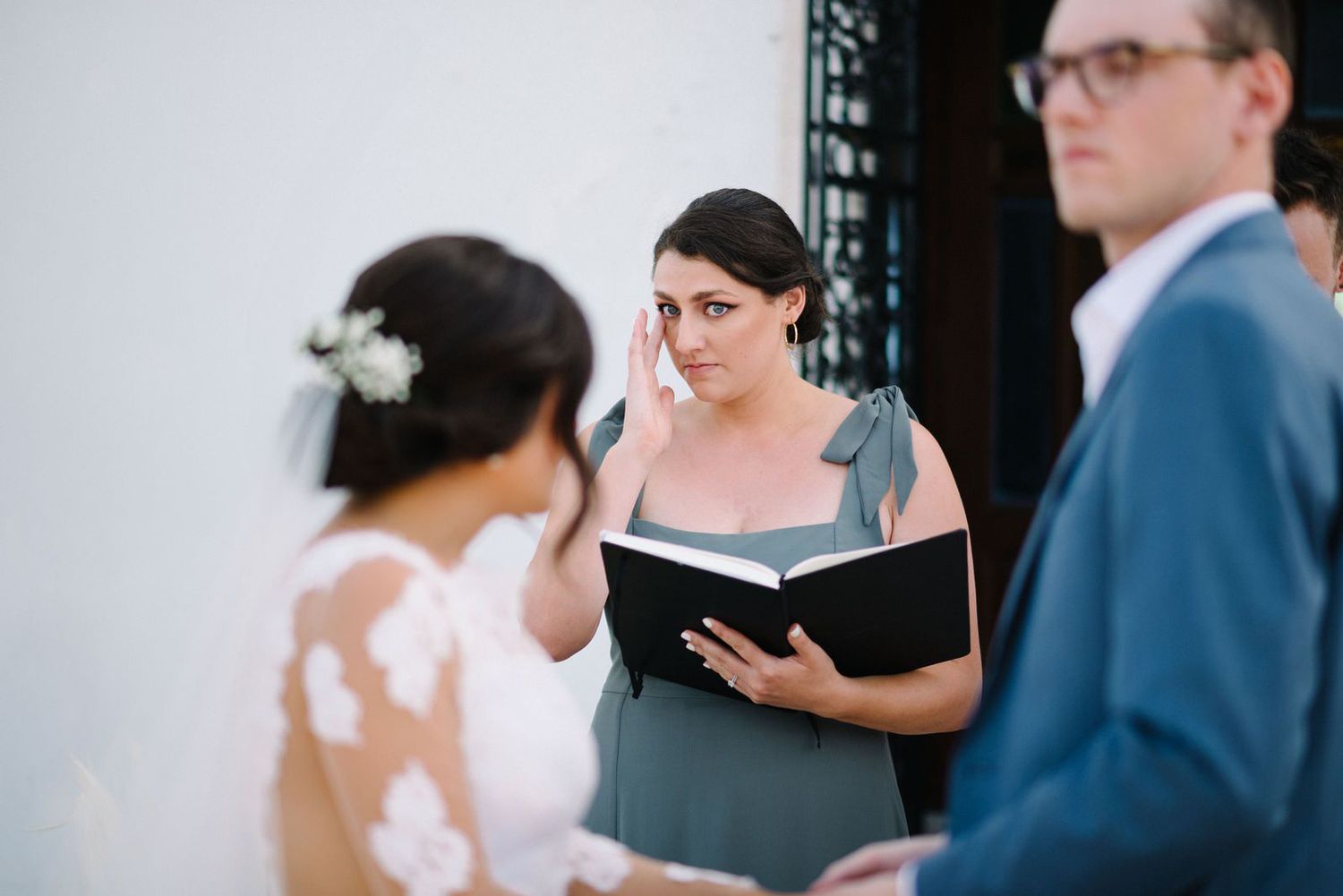 Wedding officiant reading from book during outdoor ceremony.