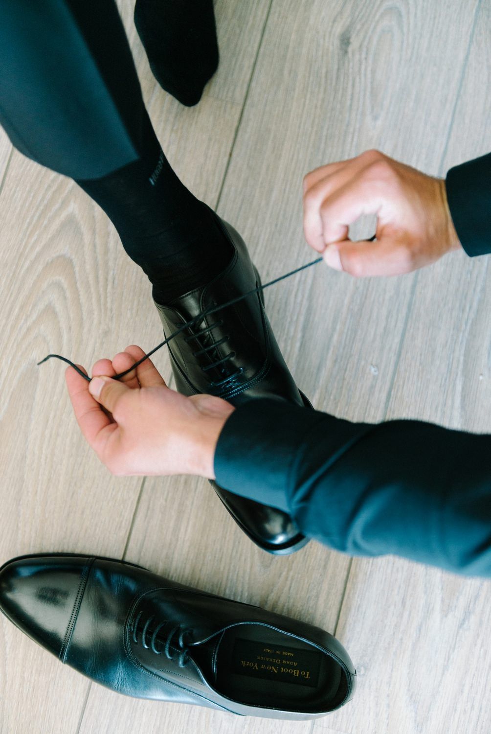 Close-up of hands tying shoelaces on black formal dress shoes.