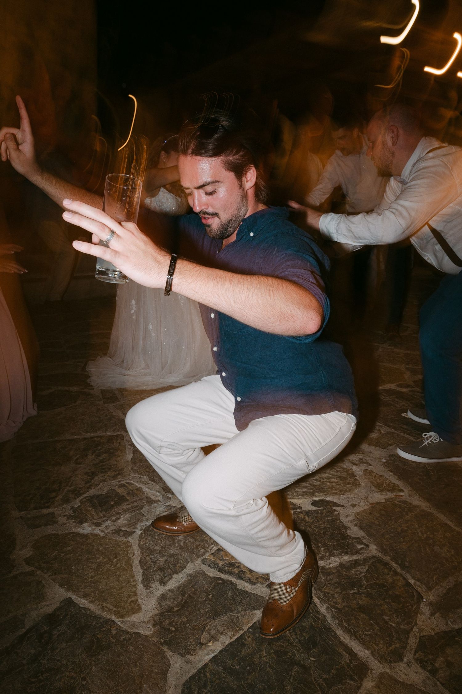 A series of action shots showing someone performing dance moves and squatting low on a stone floor in dim lighting.