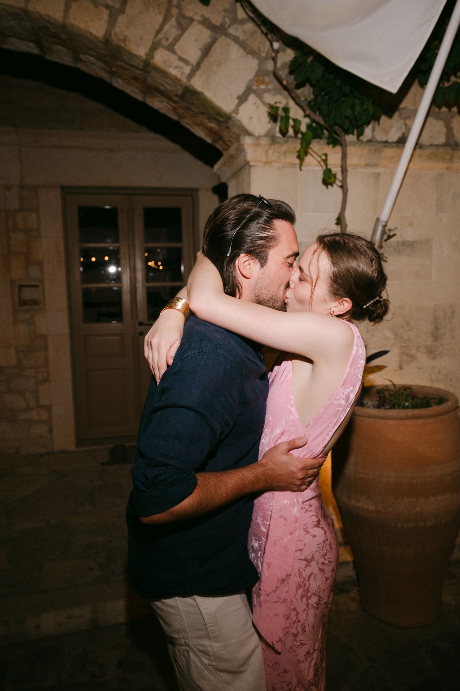 Two people share a romantic dance embrace in an atmospheric stone-walled venue with warm lighting.