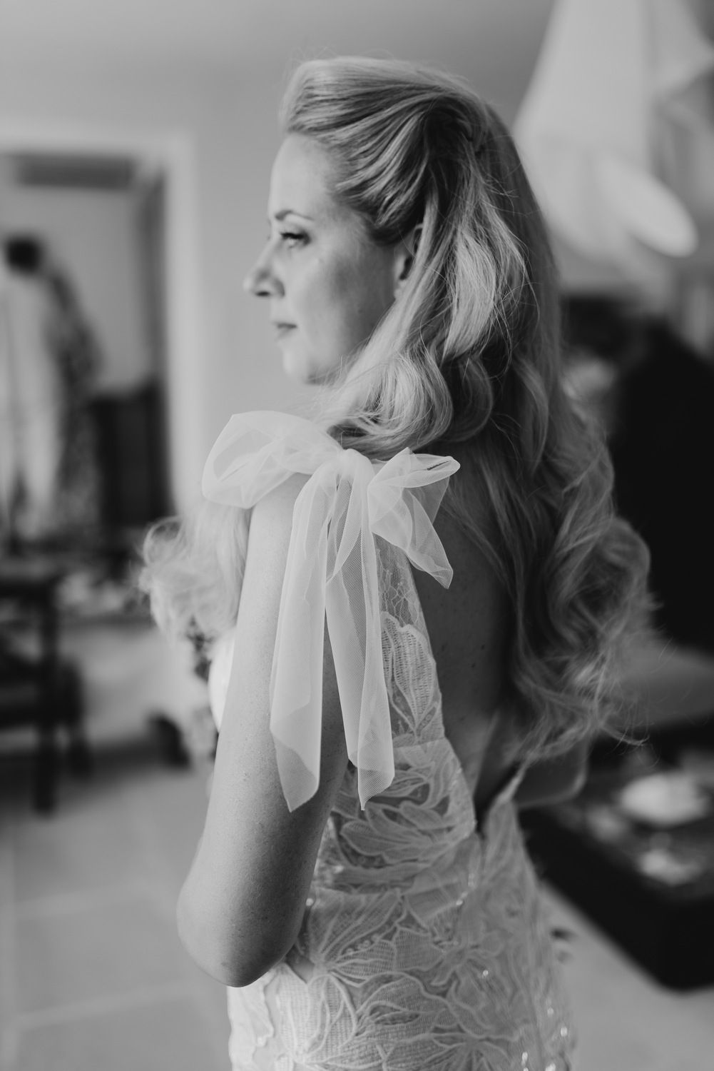 Elegant bridal hairstyle with bow detail and lace dress in black and white.