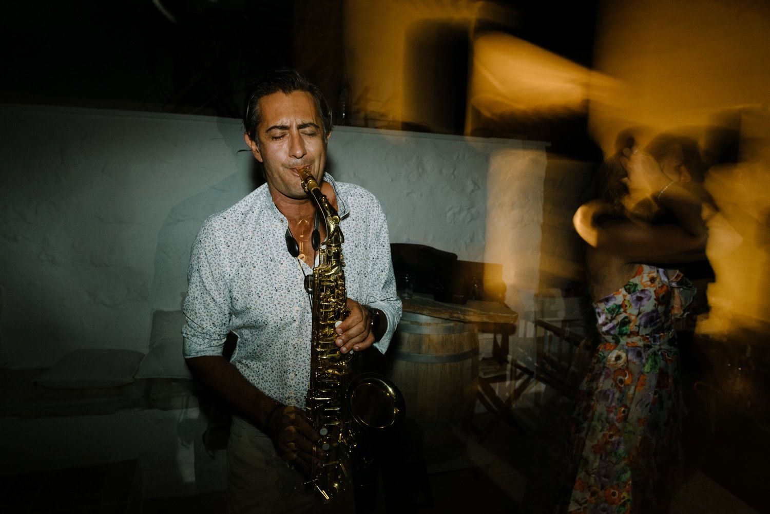 Musician plays saxophone in dramatic lighting during evening event performance.