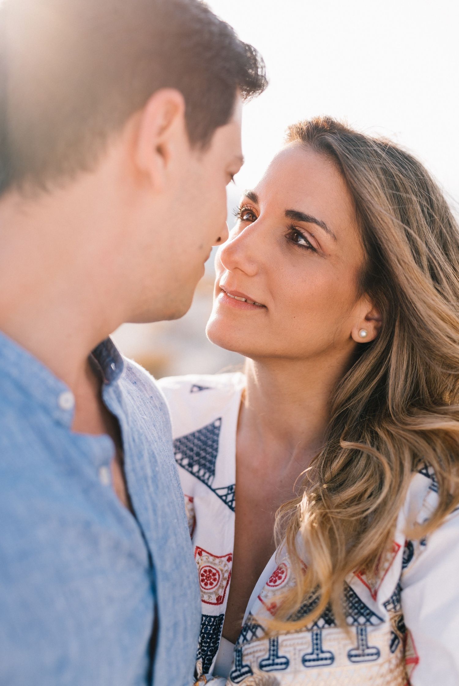 Intimate close-up of couple sharing tender moment in warm sunlight.