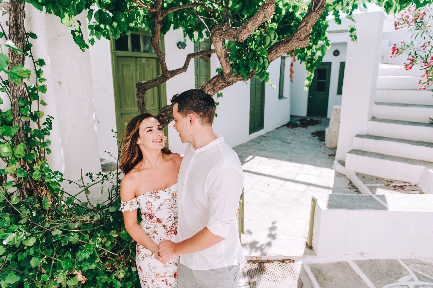 A joyful moment under green vines against white Mediterranean architecture.
