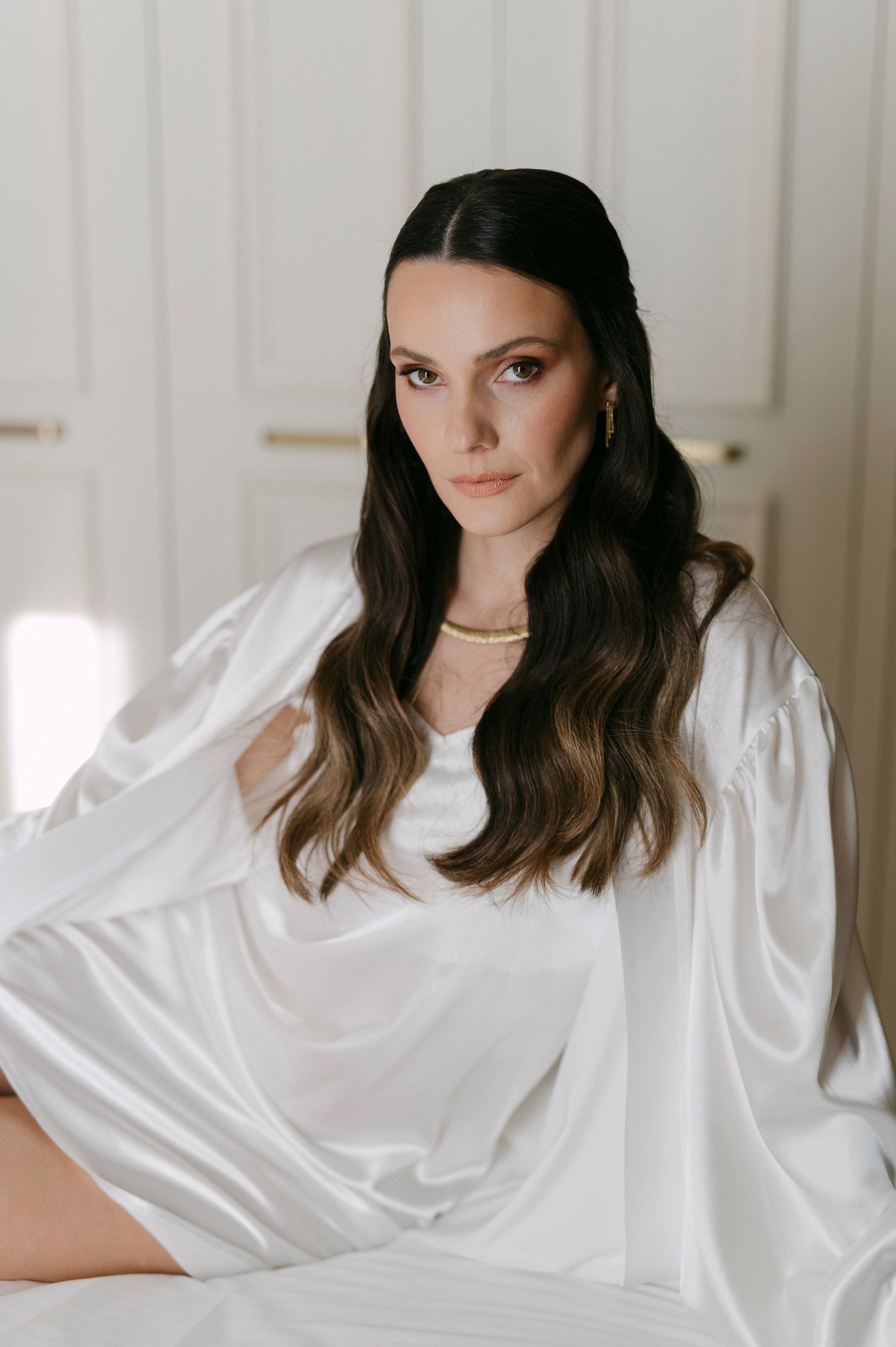 A series of four portrait photos showing someone in a white silk robe against a light background.
