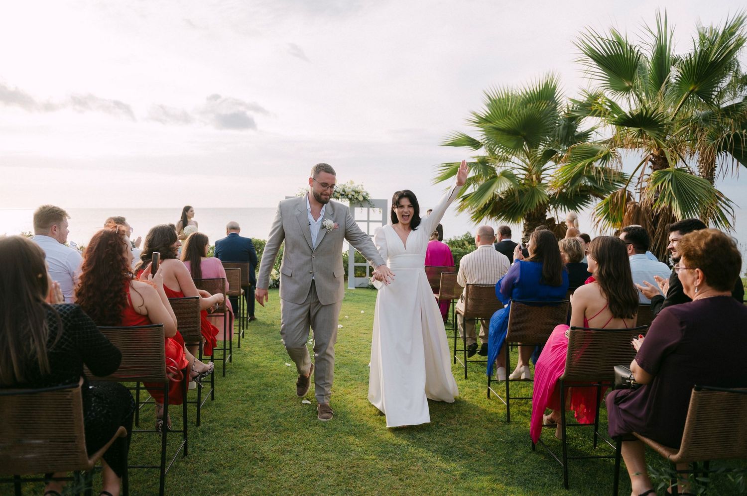 A series of outdoor wedding ceremony photos showing guests seated in chairs on a grassy lawn with palm trees in the background.