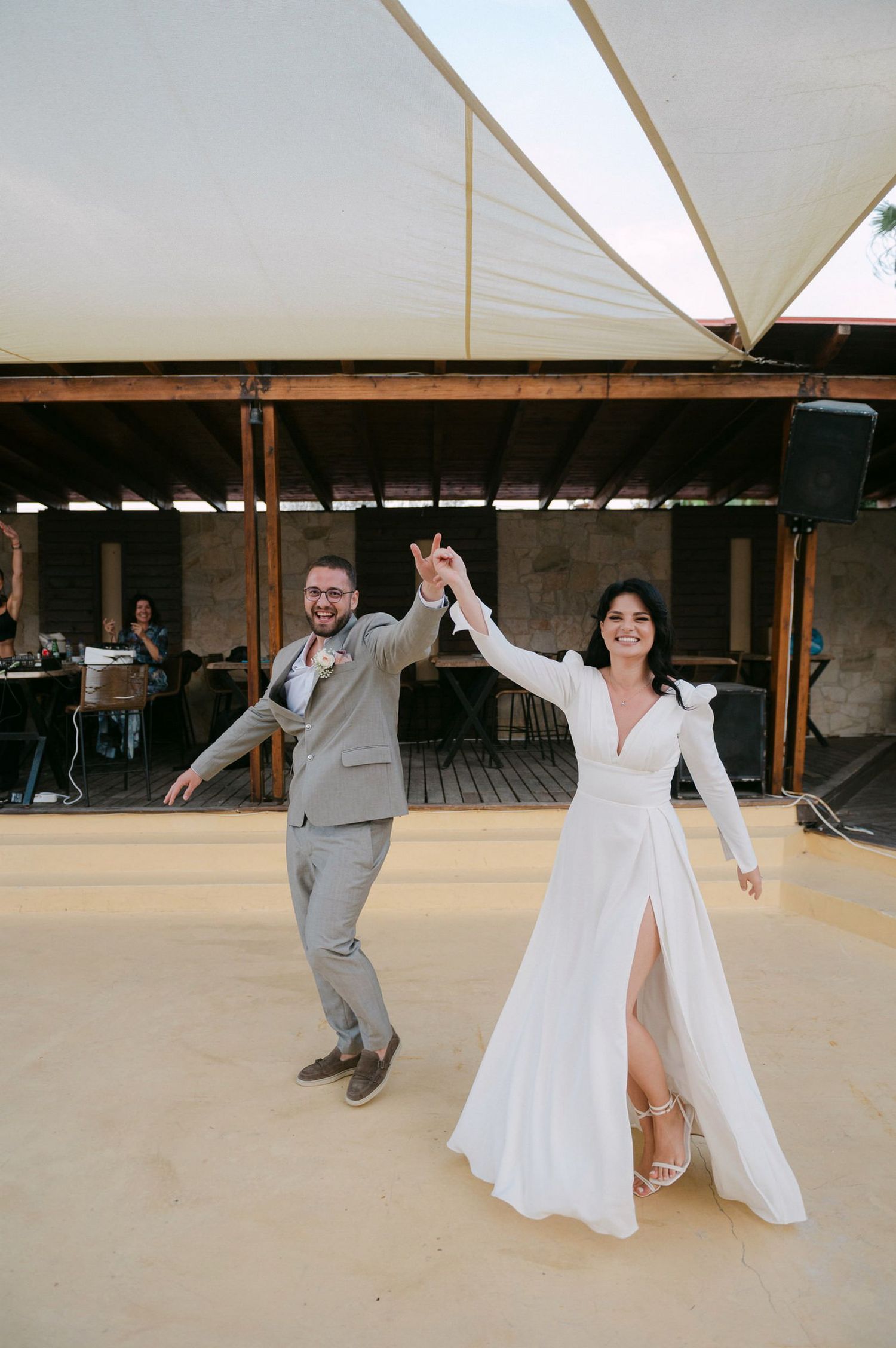 A couple performs a playful dance sequence in a rustic venue, with the bride twirling in her white gown.