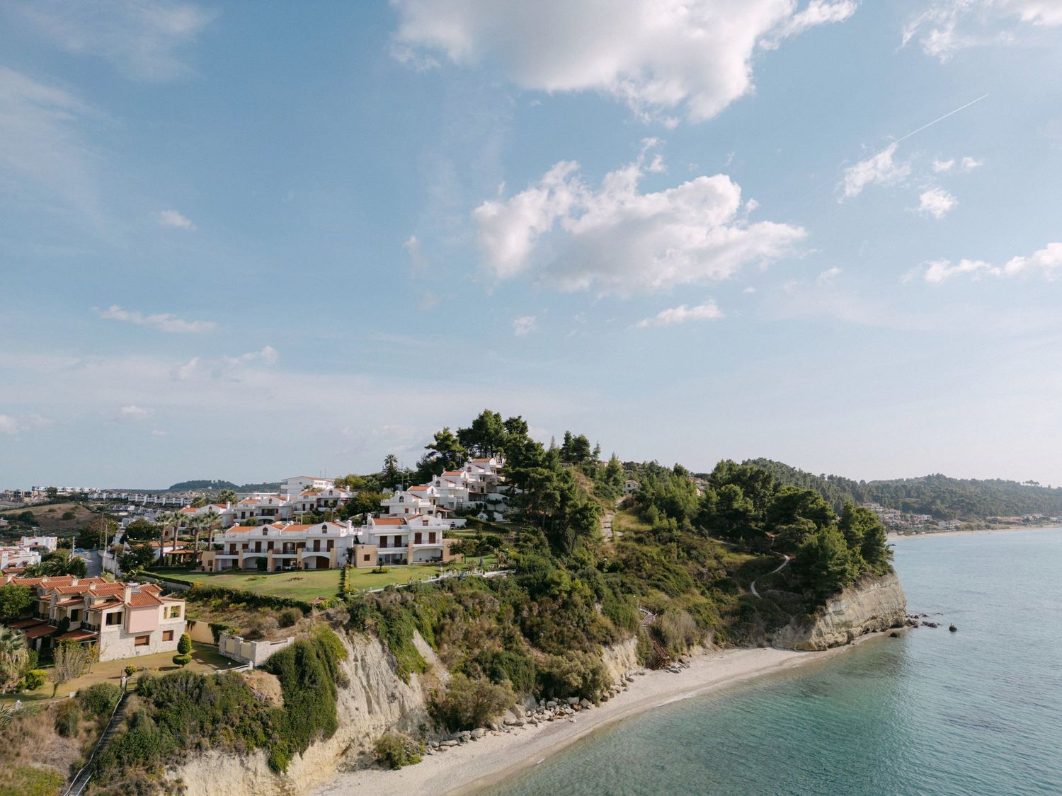 Scenic coastal view of Mediterranean houses perched on cliffs overlooking a pristine beach and turquoise waters.
