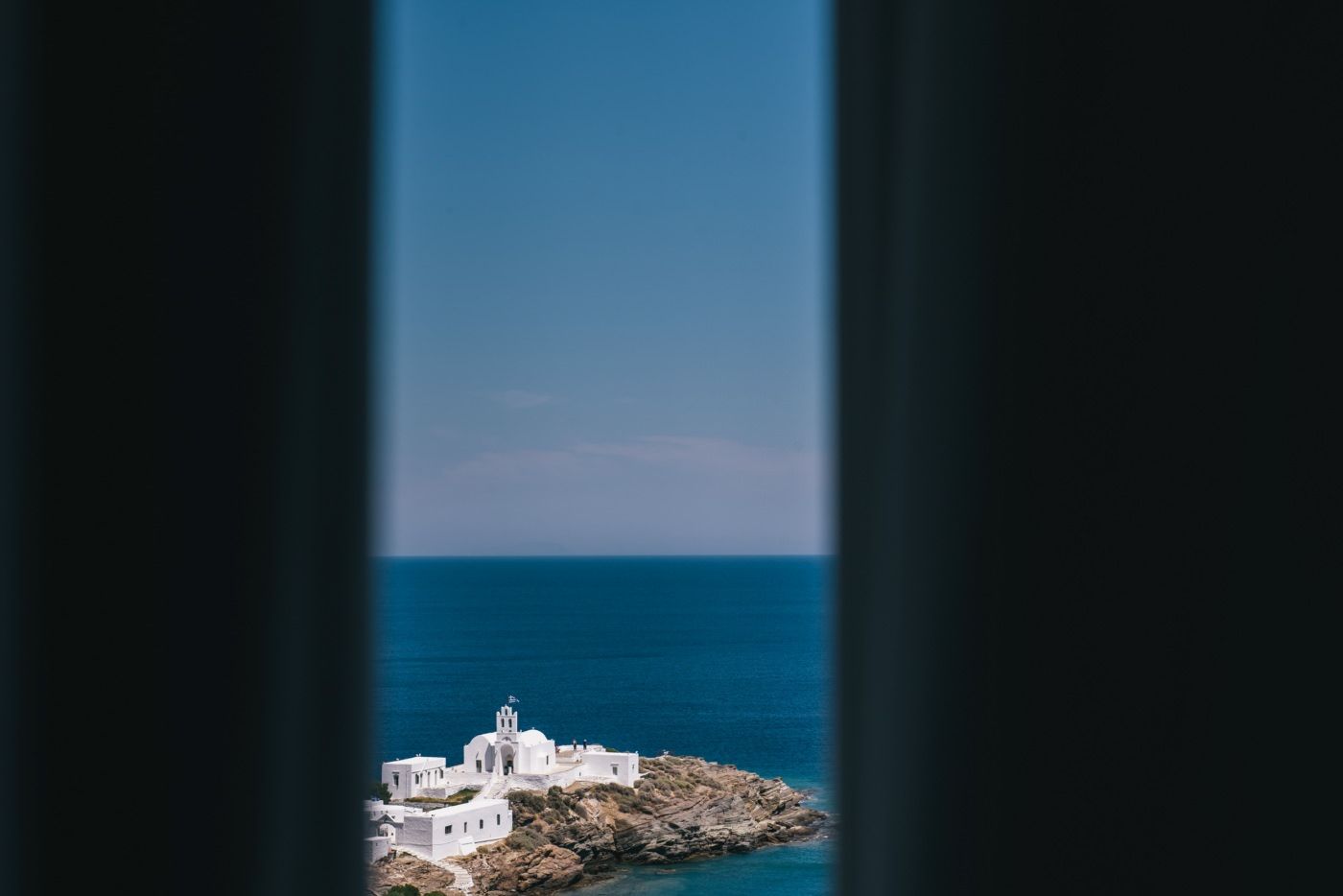 View of seaside lighthouse through narrow window frame.