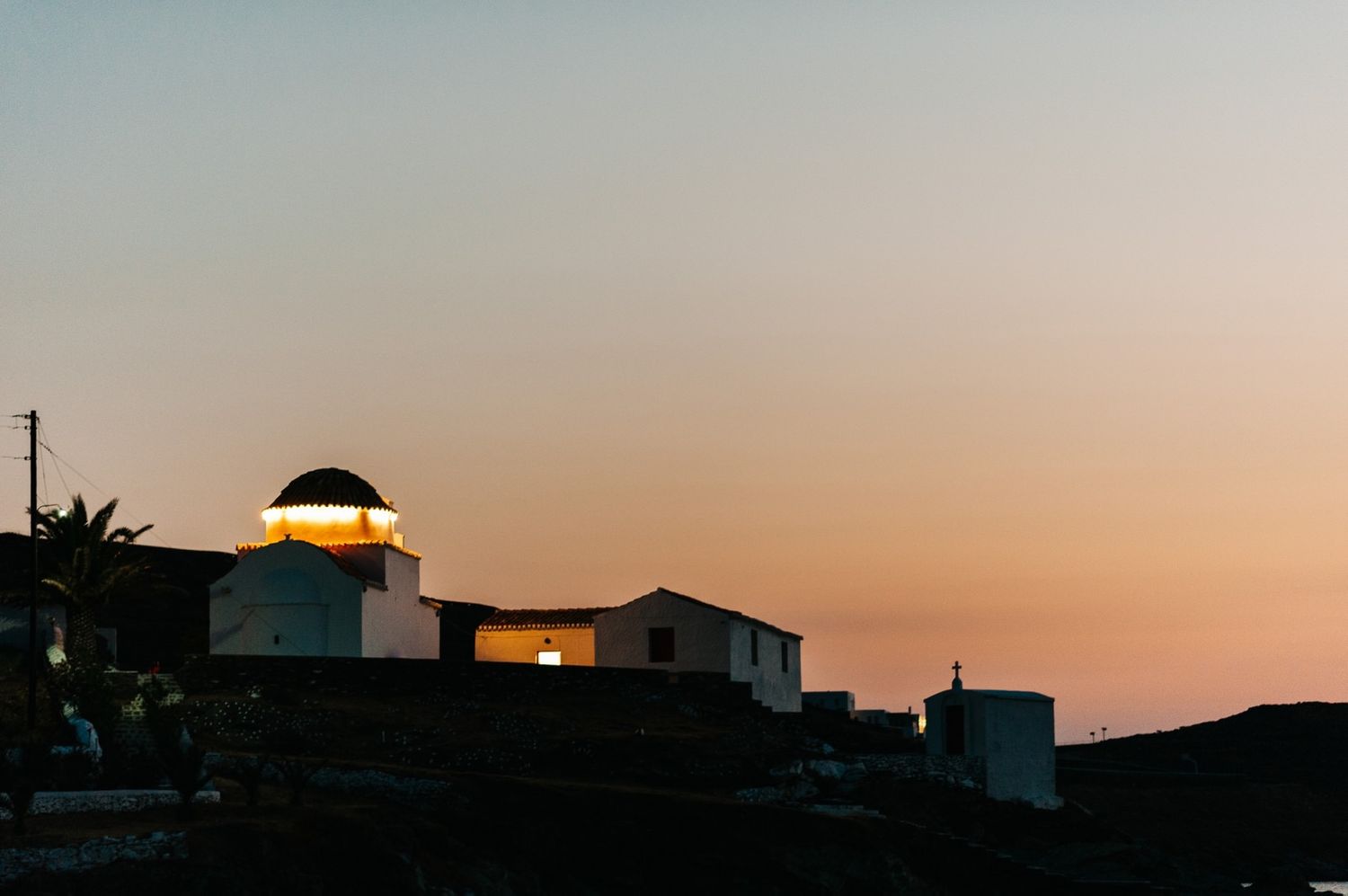 Illuminated domed church building silhouetted against sunset sky.