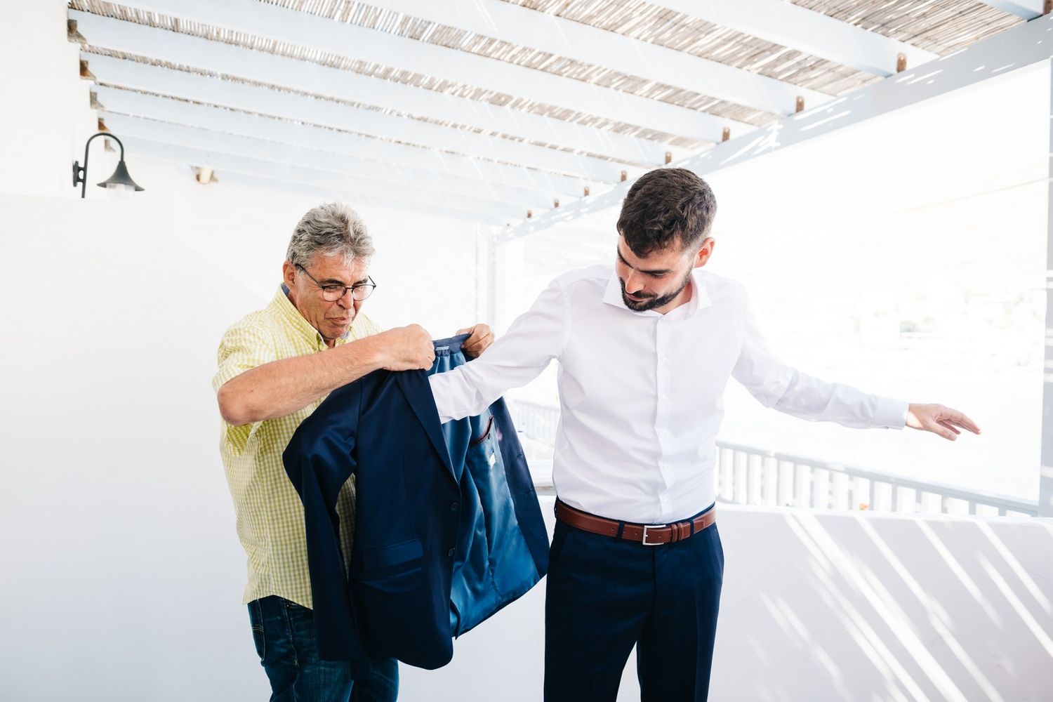 Person helping with formal attire adjustments in a bright room.
