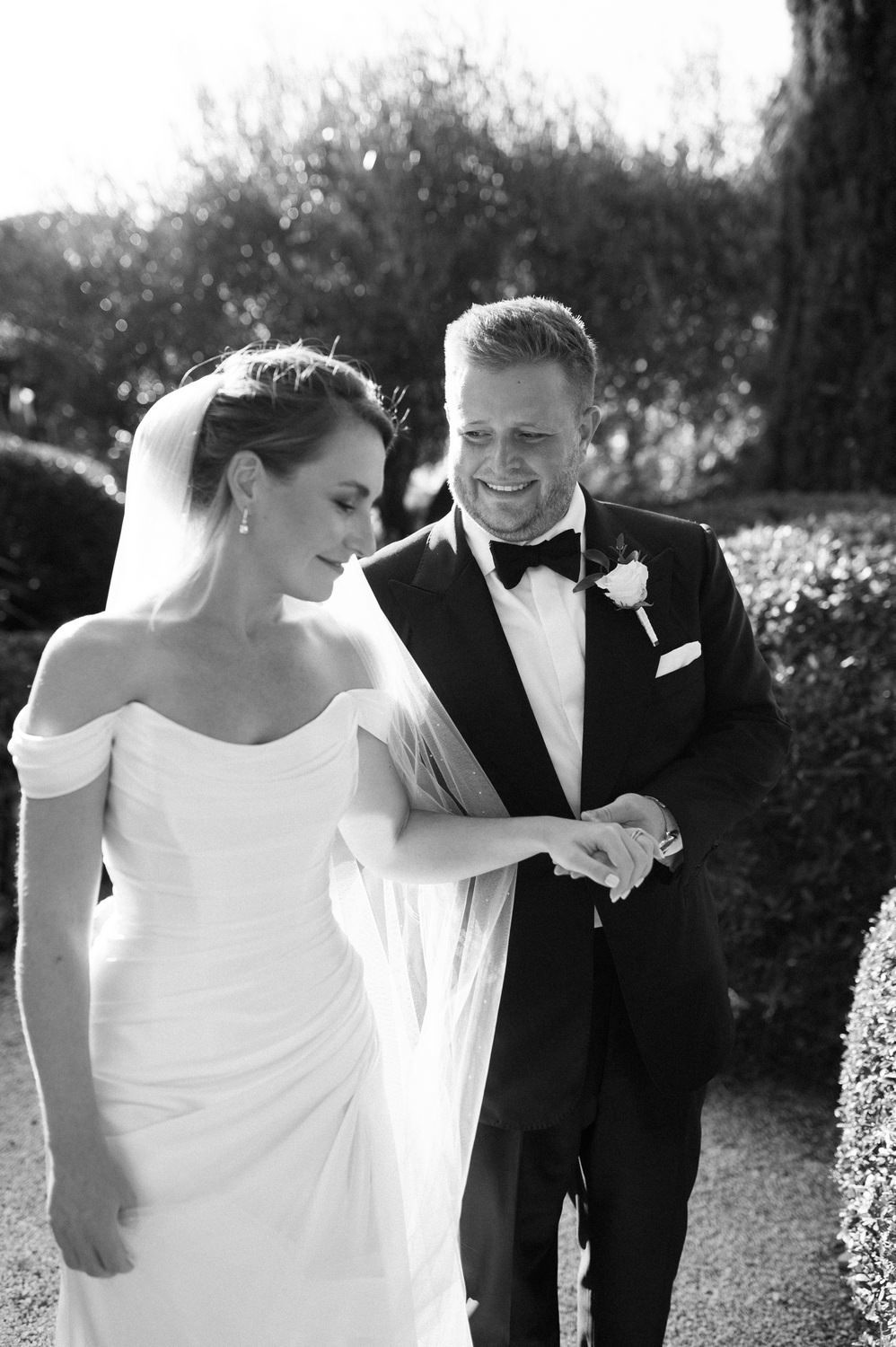 Black and white portrait of happy newlyweds sharing candid moment outdoors.
