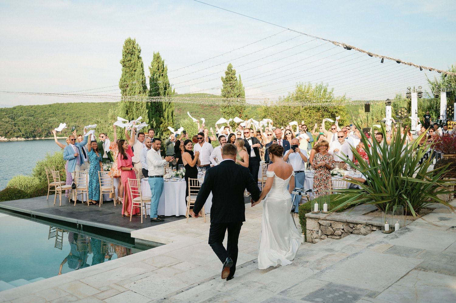 Wedding celebration by a poolside with guests cheering.
