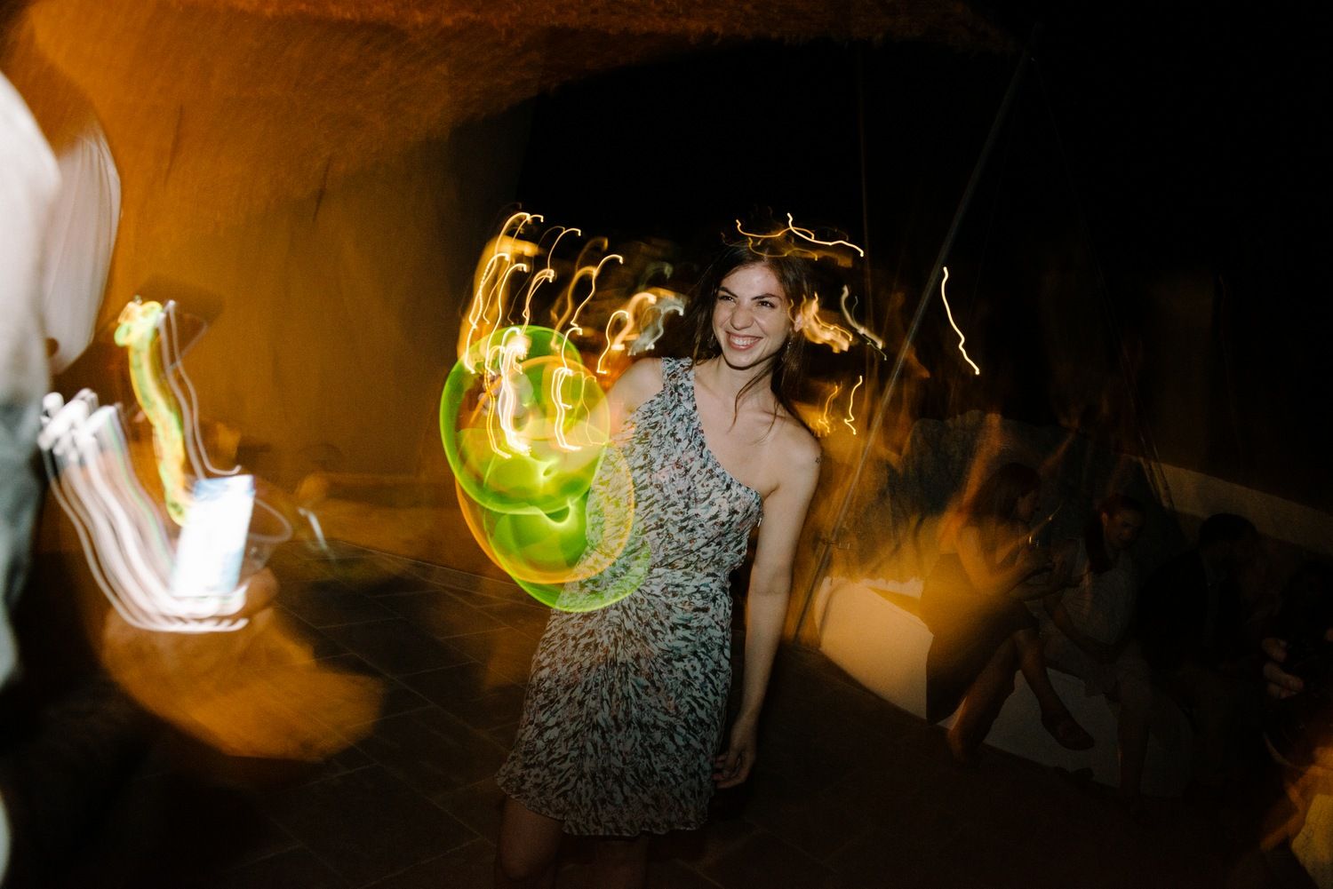 Guest dancing at nighttime party with colorful light trails and motion blur effects.
