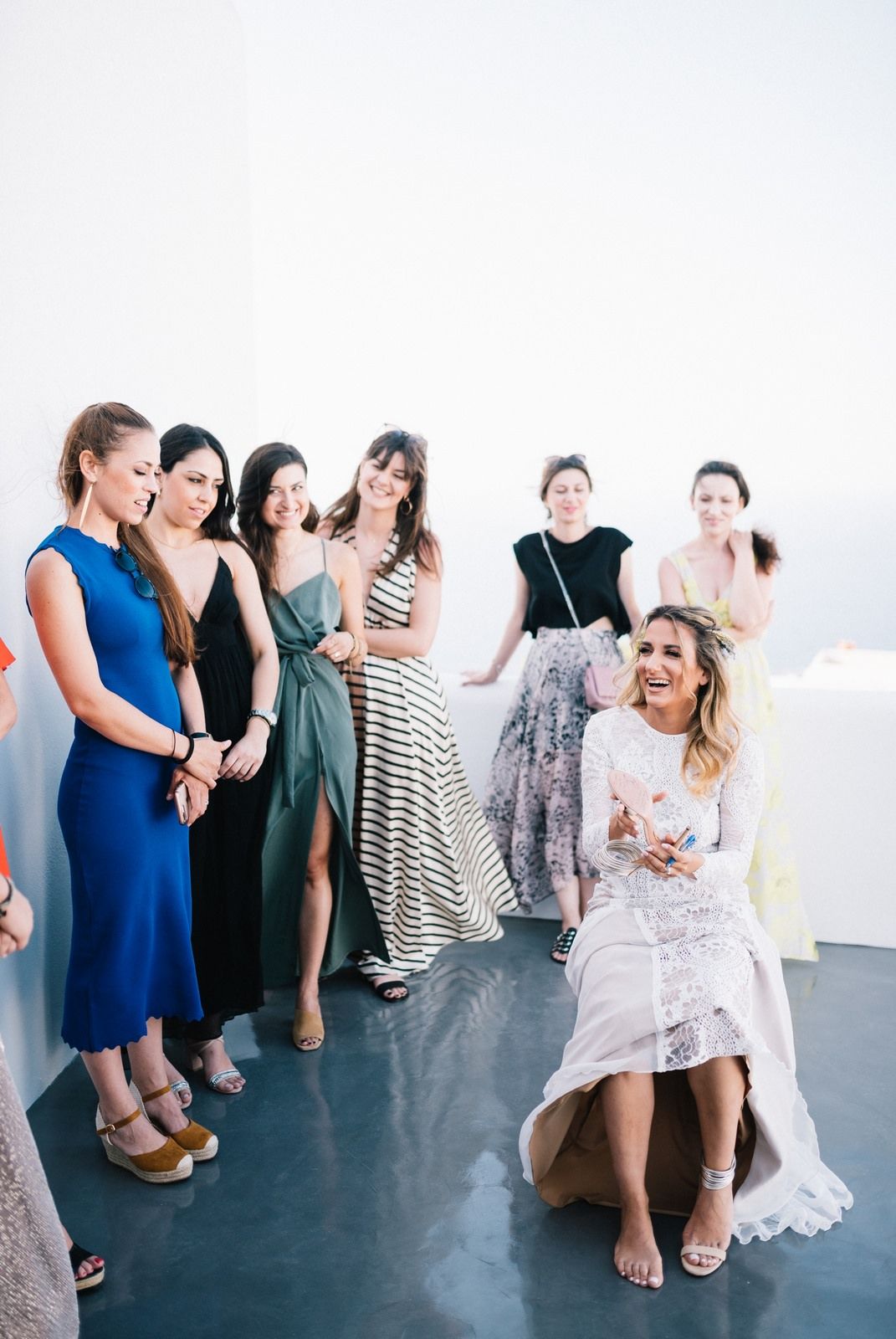 Group of women in formal dresses laughing and celebrating at wedding preparation.