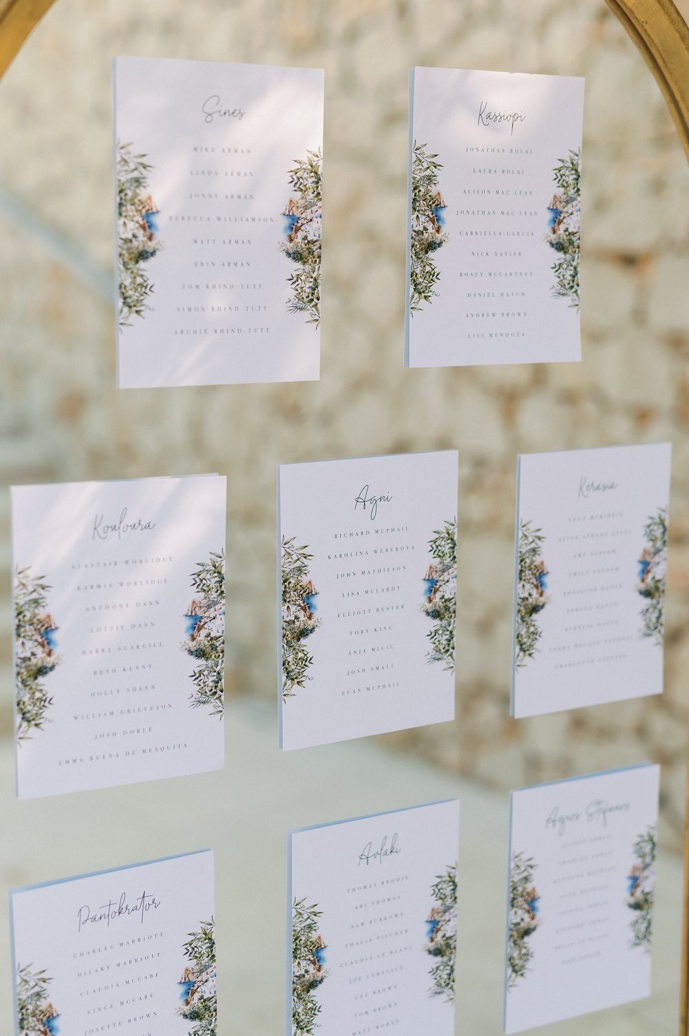 Wedding seating chart with floral design displayed on gold mirrored surface.