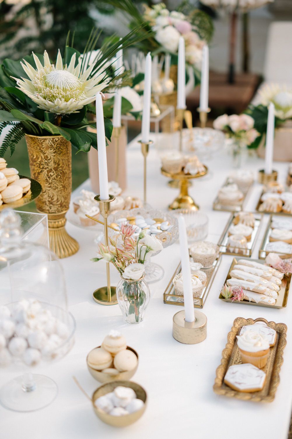 Elegant wedding table setting with gold accents, white flowers, and candles.