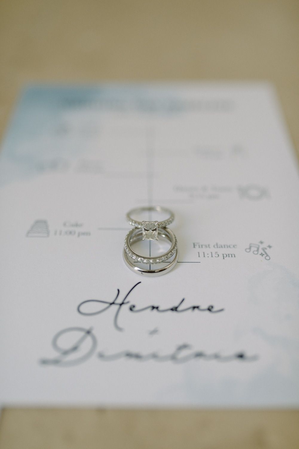 Diamond wedding rings displayed on an elegant wedding invitation with calligraphy text.