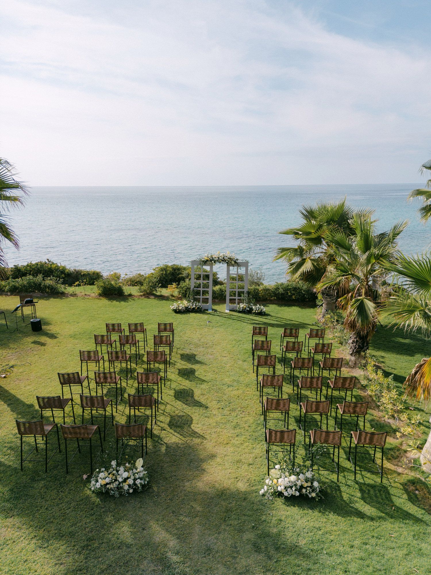 Outdoor wedding ceremony setup with wooden chairs and floral arrangements overlooking the sea at Haldidiki Greece.