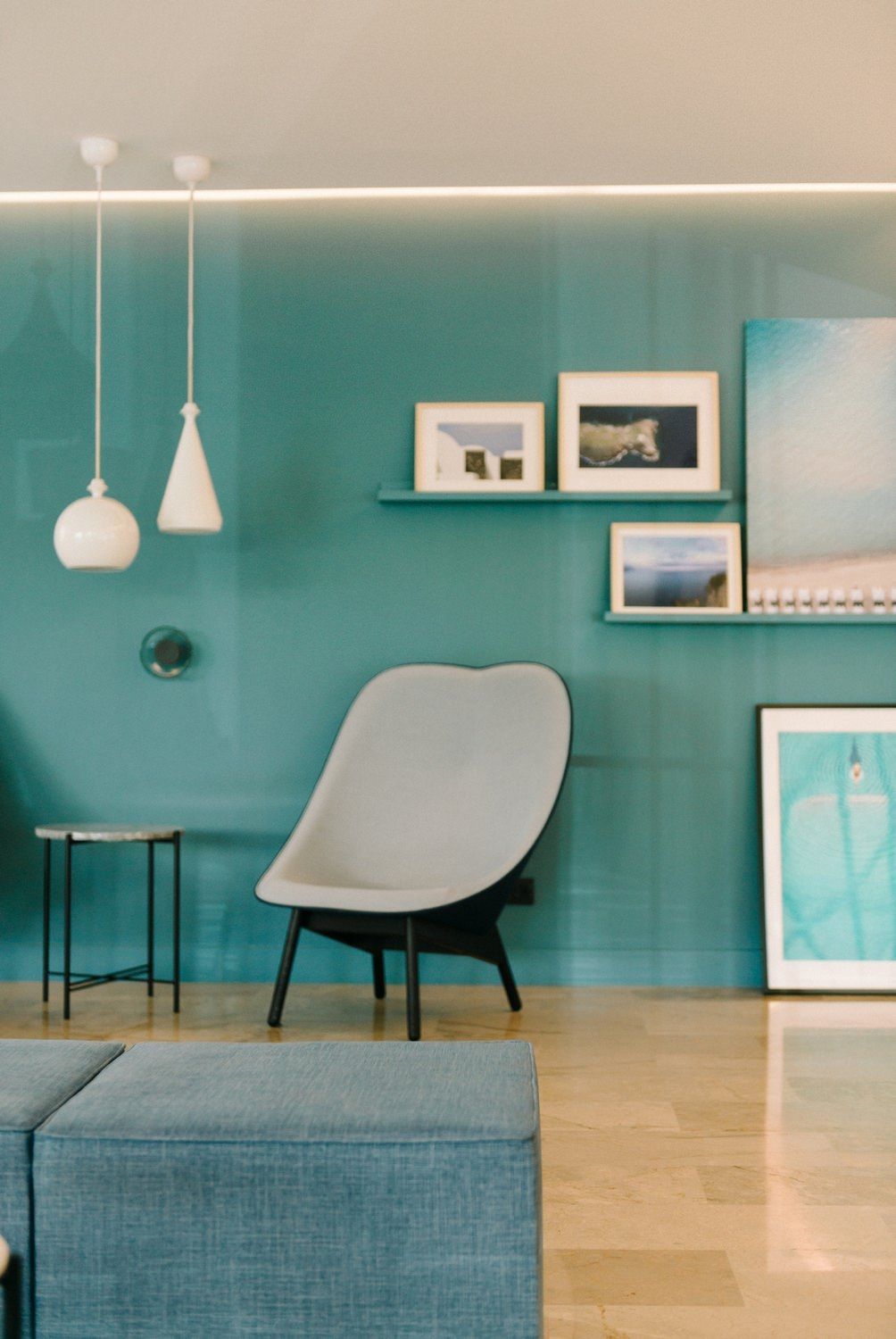 Modern interior with teal wall, pendant lights, and framed artwork displaying a minimalist aesthetic.