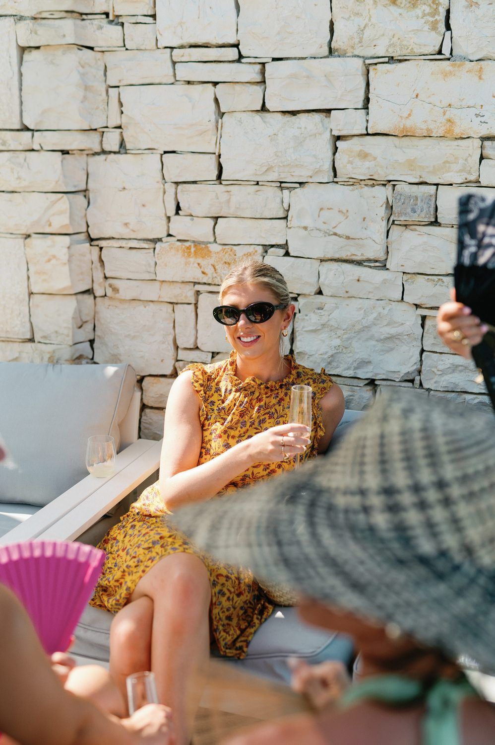 A guest in a yellow dress relaxes on outdoor furniture during a social gathering.