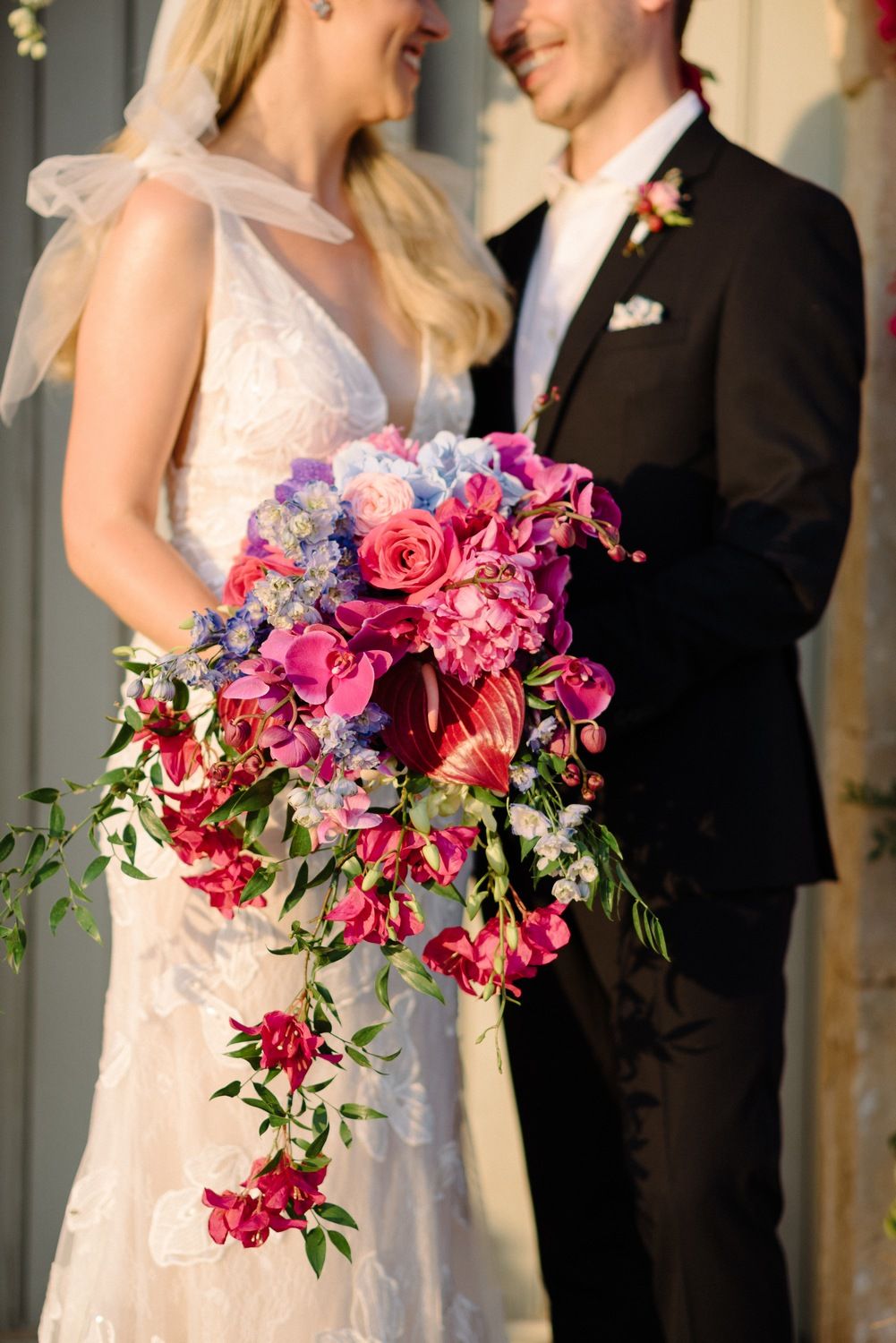 Close up of a cascading bridal bouquet with pink and purple flowers.