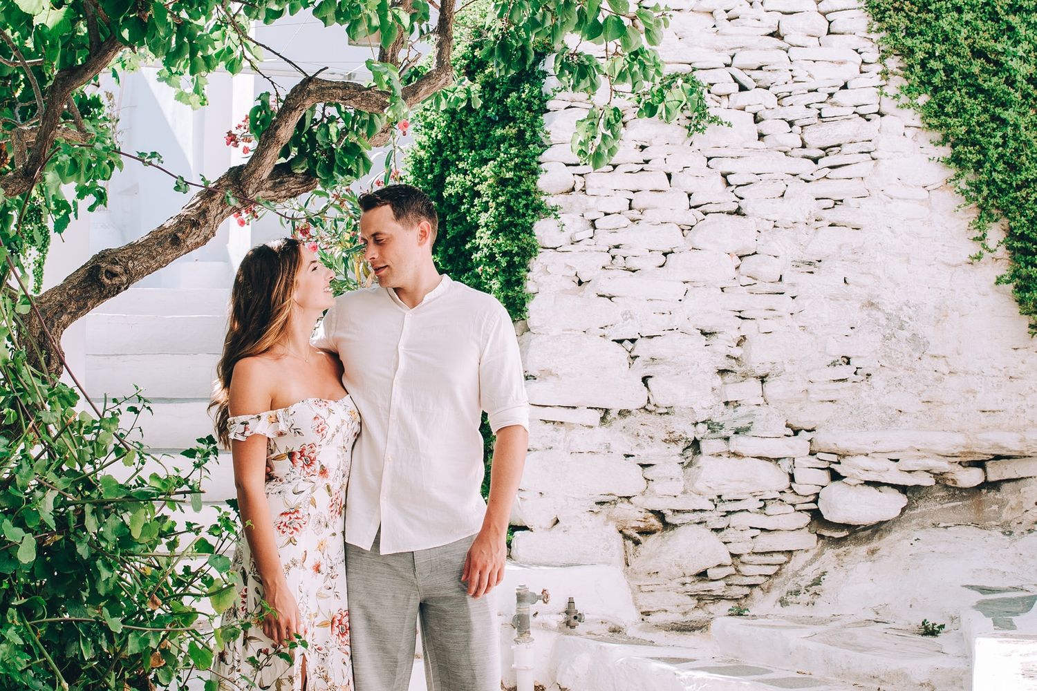 A romantic scene beside vine-covered stone walls in a Mediterranean courtyard.