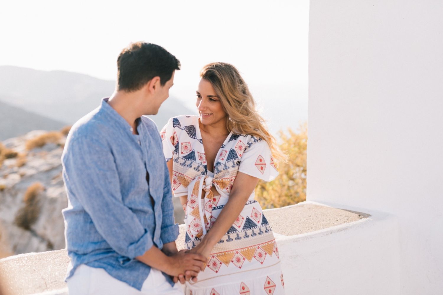 Couple shares intimate moment on Mediterranean terrace with scenic mountain backdrop.