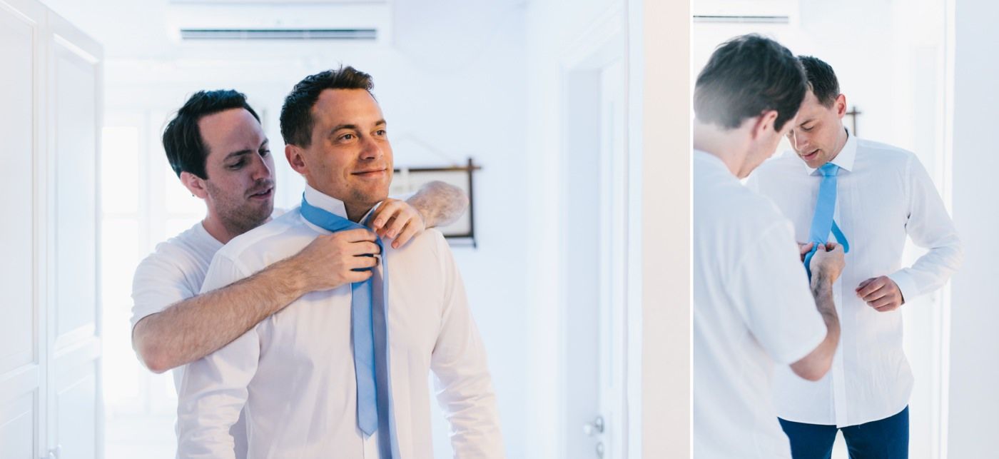 Wedding preparation scene of formal attire adjustments in bright white room.