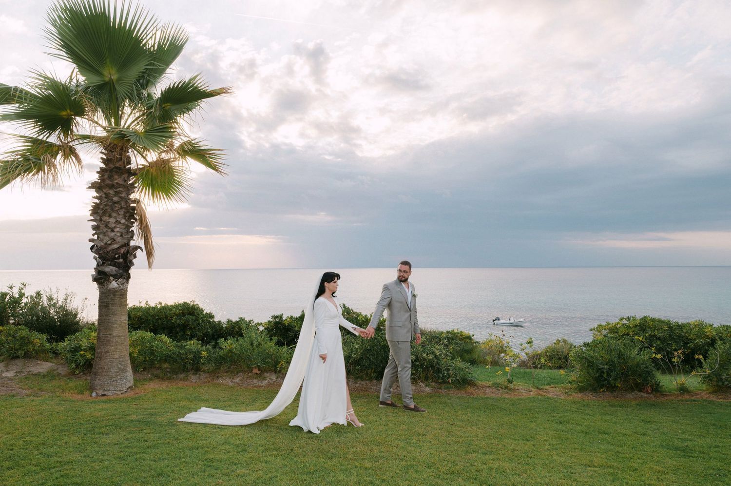 Elegant wedding ceremony set against a coastal backdrop with palm trees and cloudy skies.