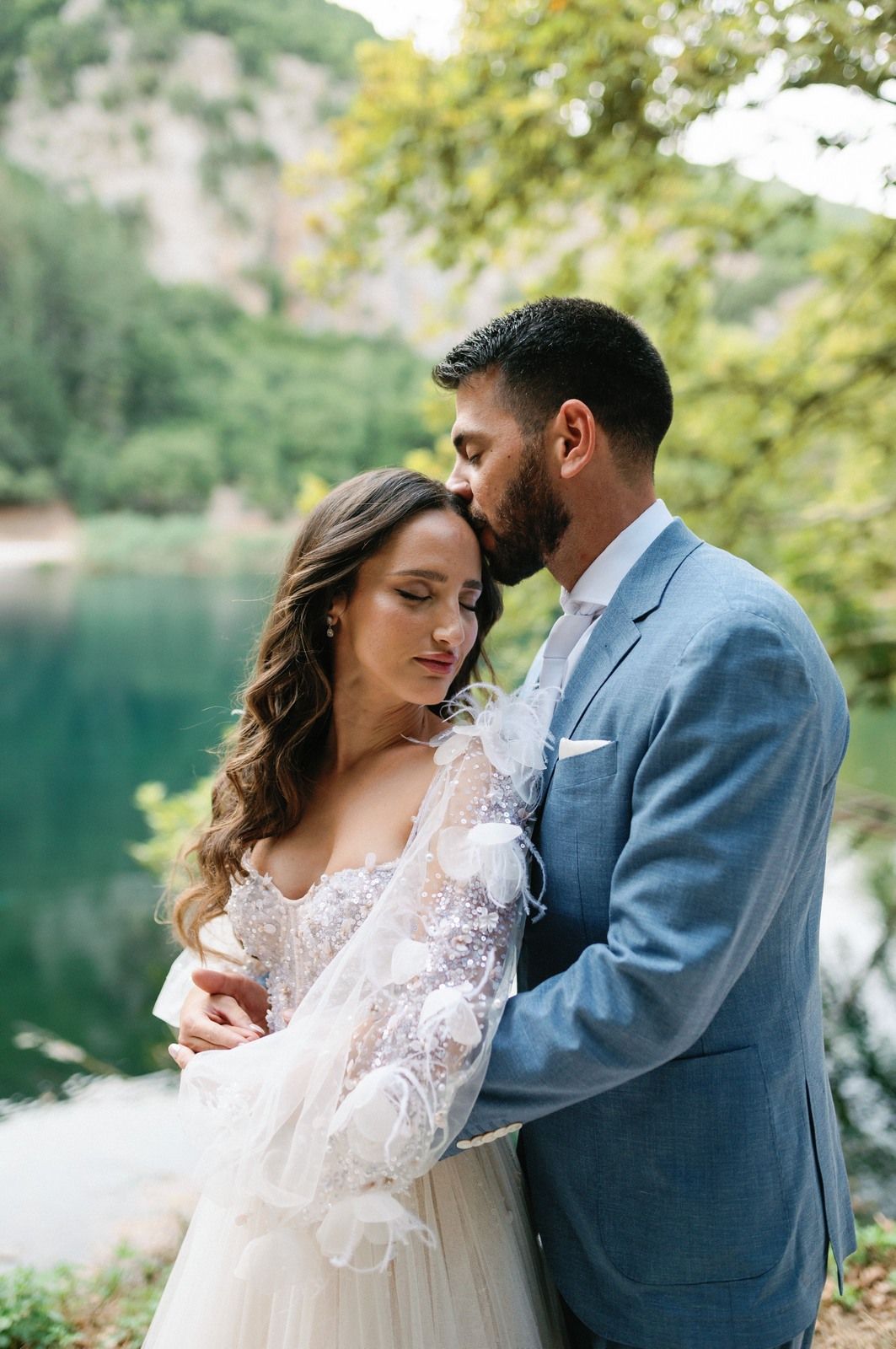 Romantic wedding couple embraces near a serene lake surrounded by lush greenery in a series of intimate moments.