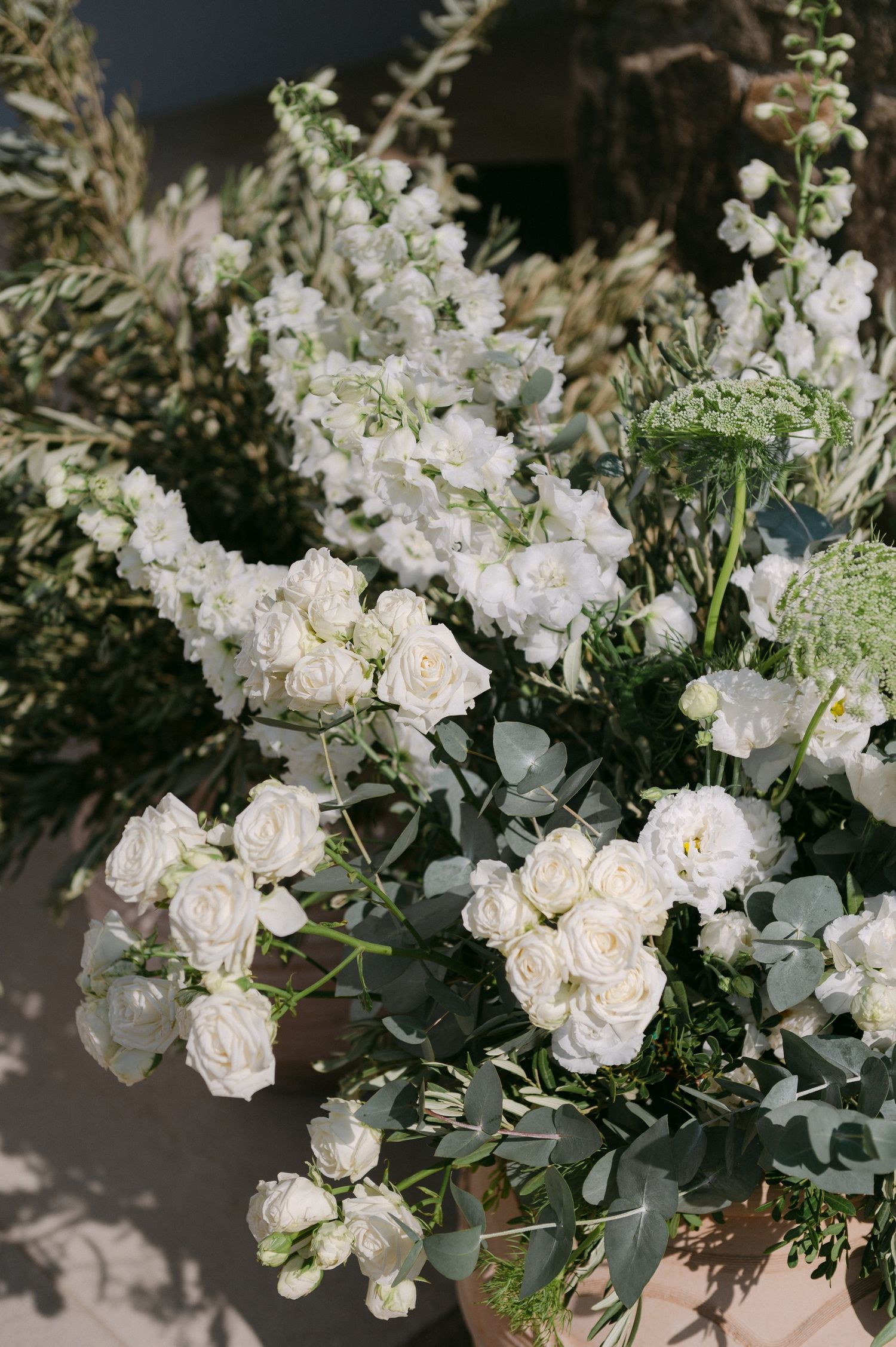 Elegant white rose and eucalyptus floral arrangements displayed in a series of connected images against dark background.