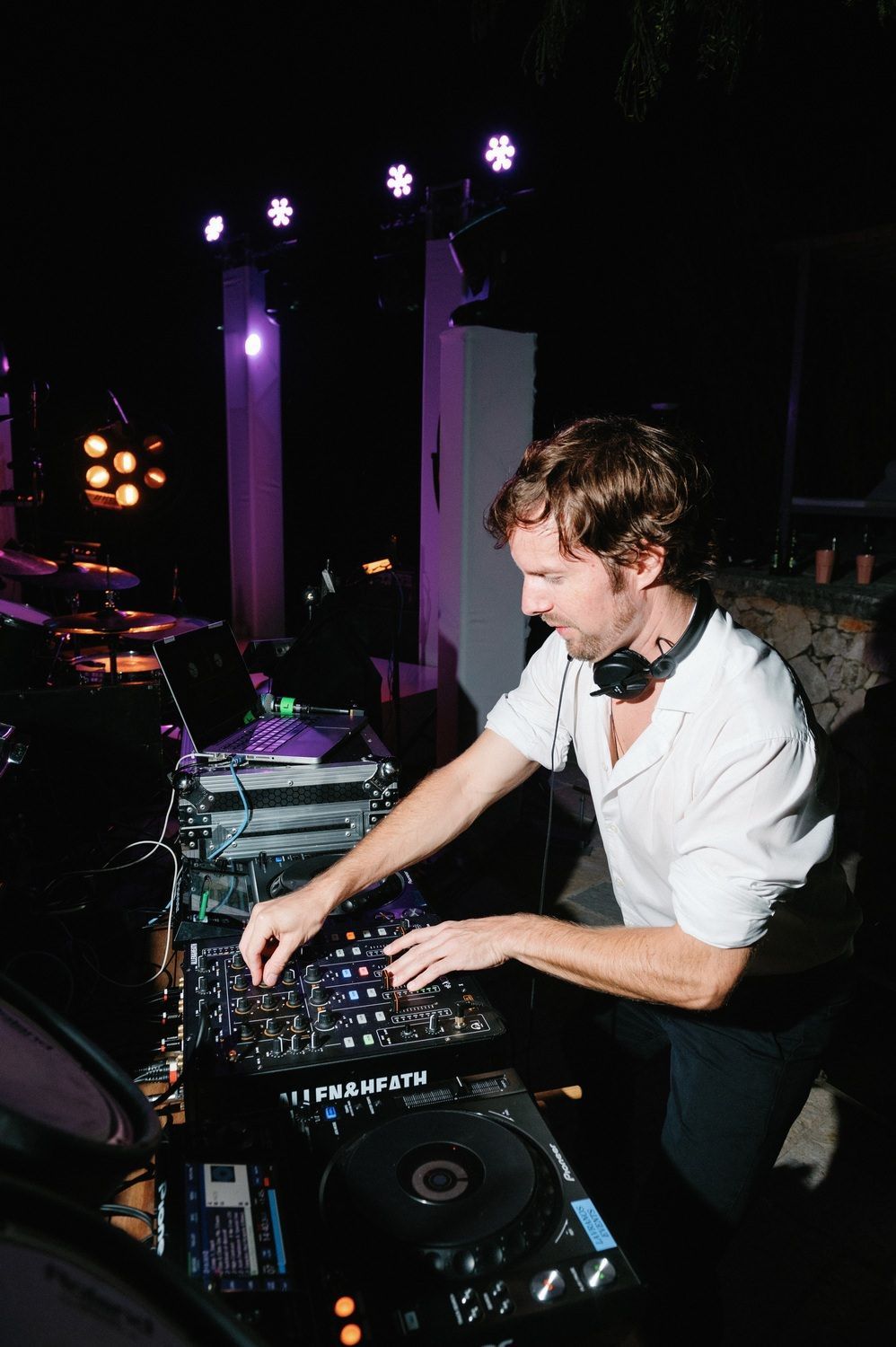 DJ performing at a nightclub with professional audio equipment and turntables in a dark atmospheric setting.