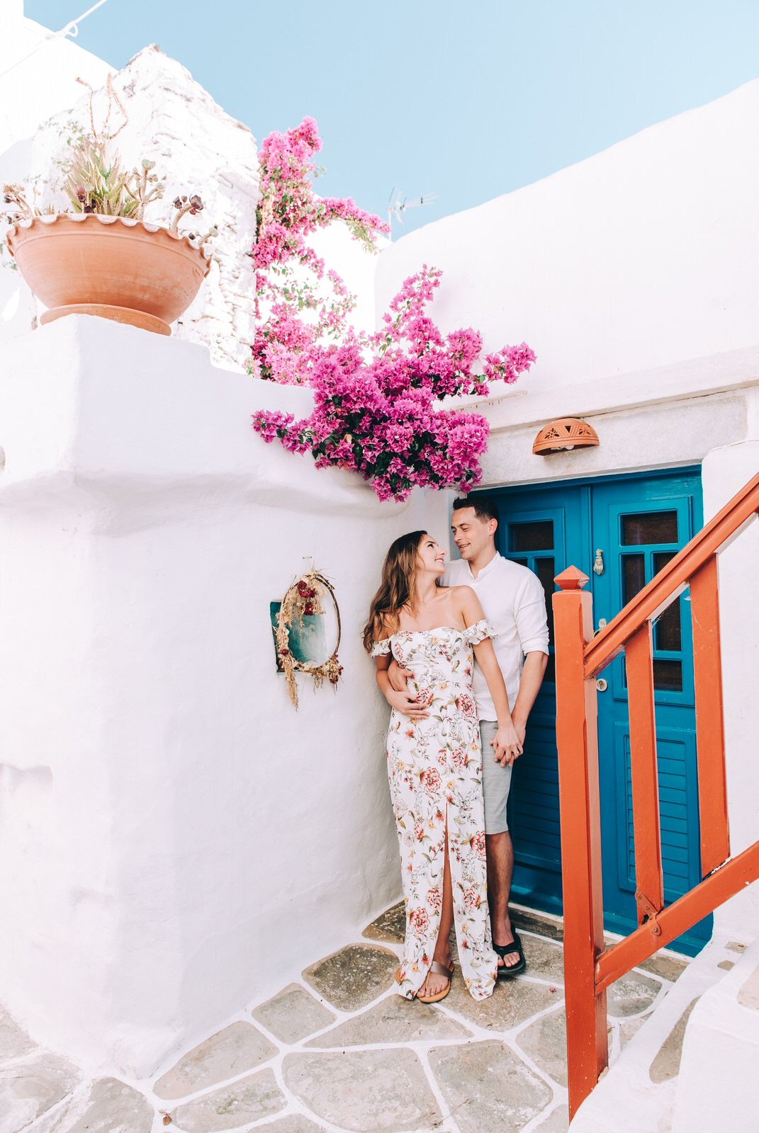 Romantic photoshoot under blooming bougainvillea near blue door in Mediterranean setting.