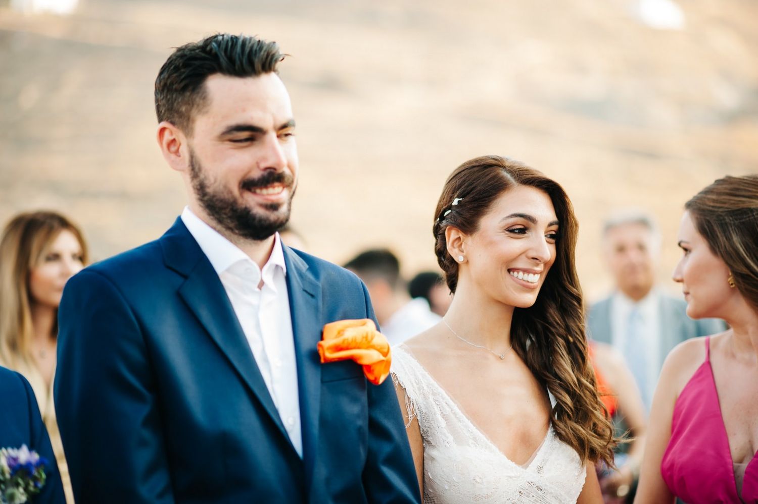 Joyful outdoor wedding moment with couple in navy suit and white dress against mountain backdrop.