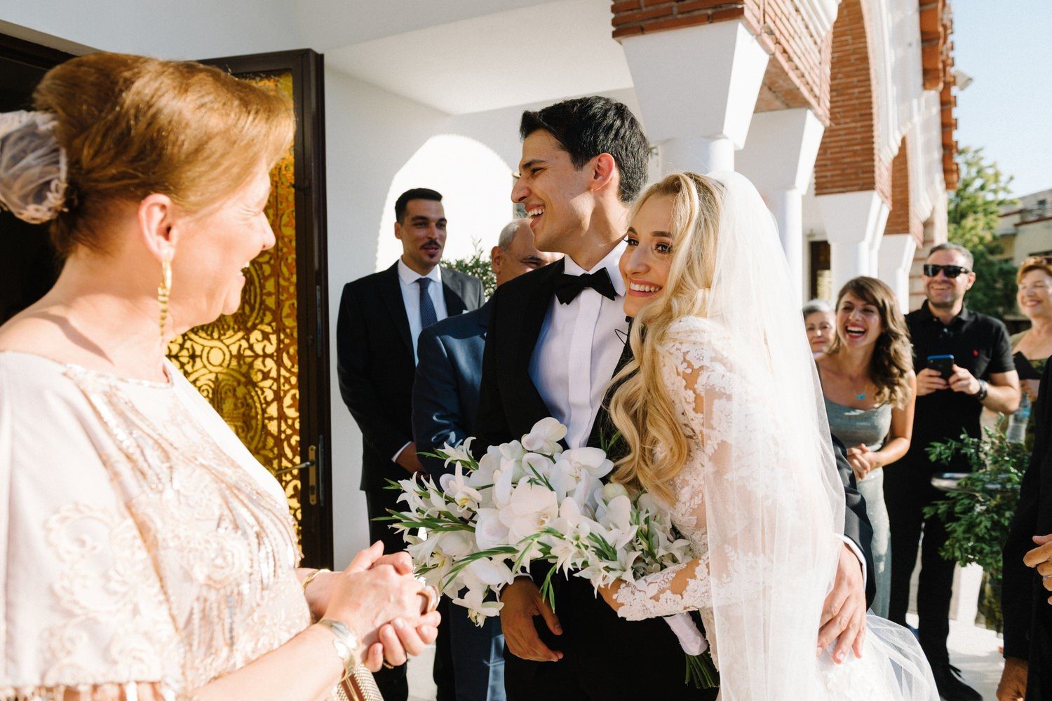 Wedding party gathers in a bright hallway during an intimate ceremony moment.