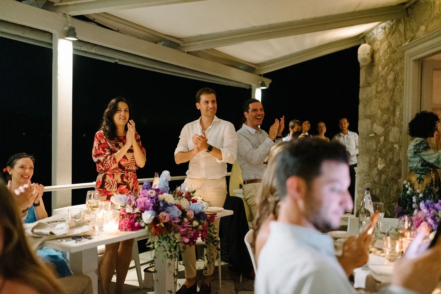 Evening wedding reception with guests celebrating in an outdoor stone terrace setting.