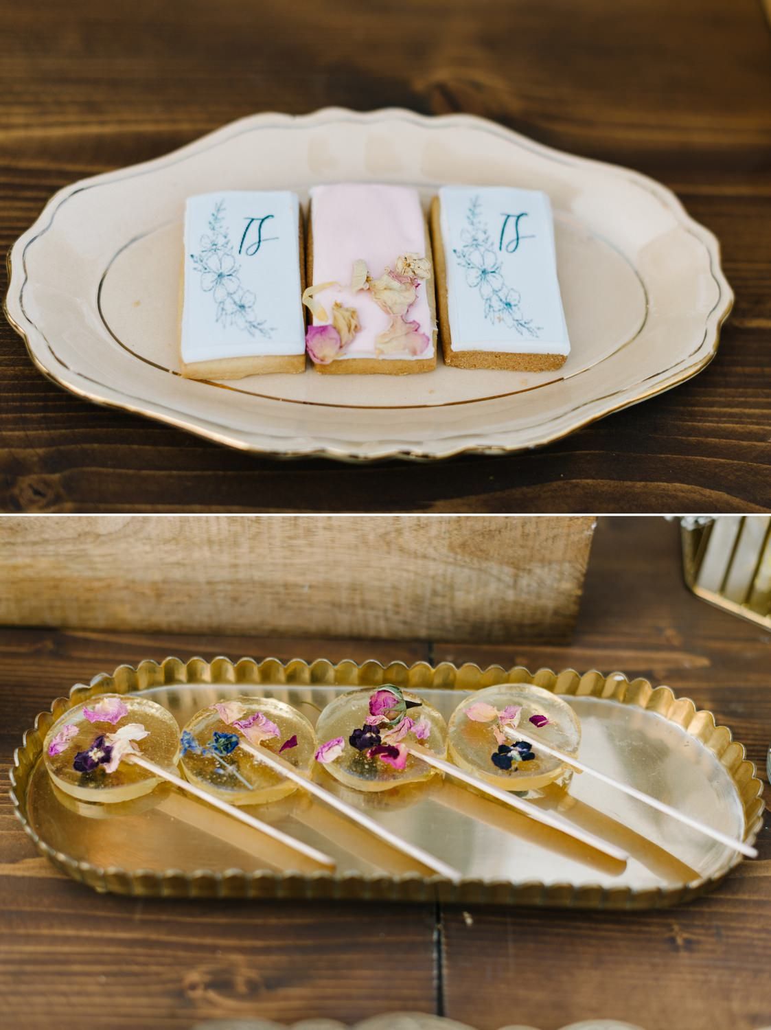 Decorative cookies and candied lollipops with floral designs displayed on ornate serving plates.